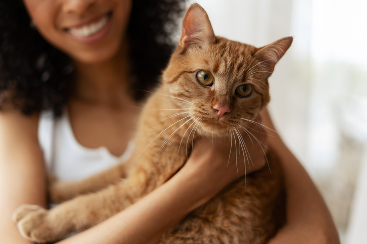 Smiling Woman Holding a Ginger Cat