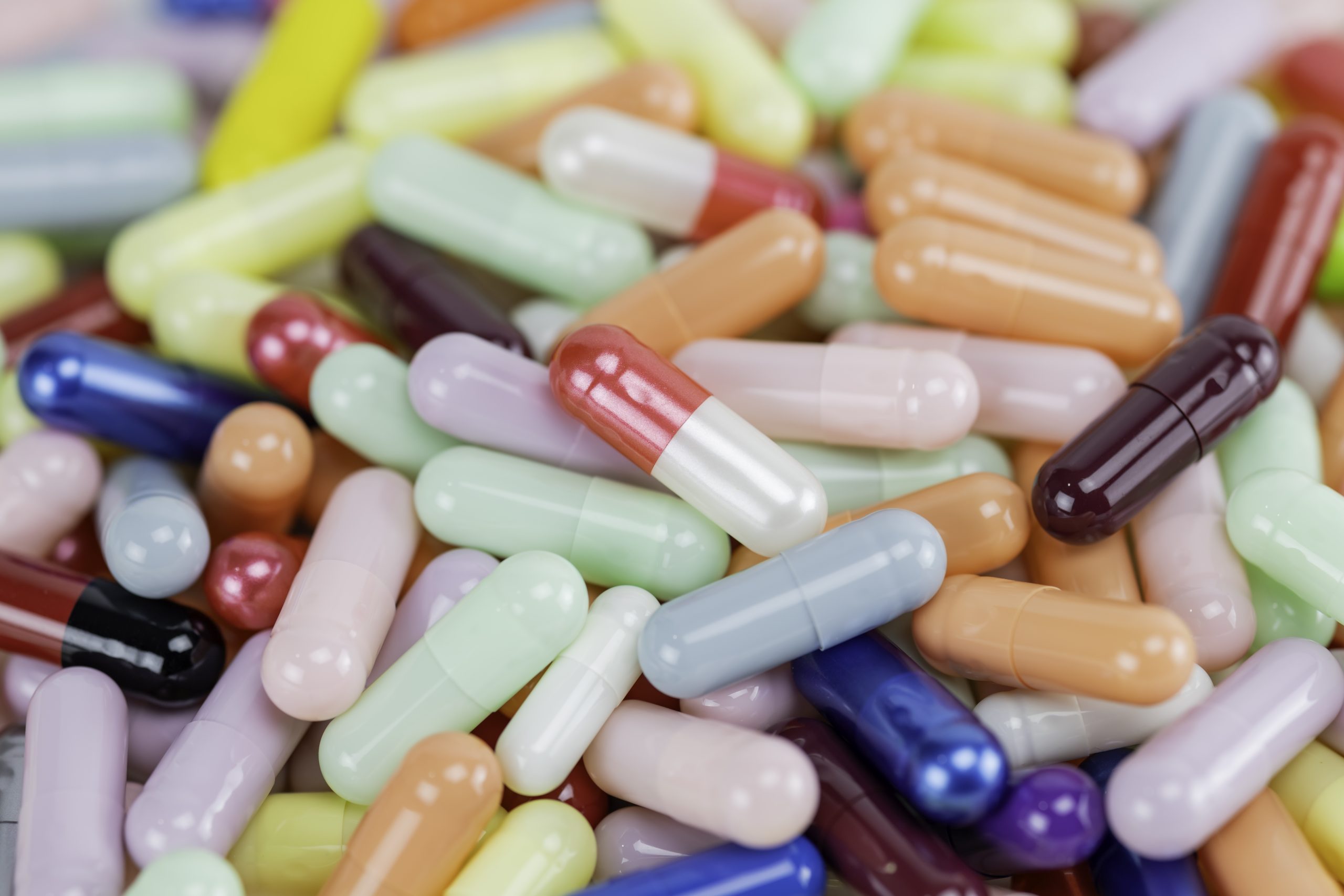 Top view flat lay of colorful medicine capsules. A background texture of various pharmaceutical pills, drugs, and antibiotics for the healthcare and supplement industry. Concept of pharmacy and medication.